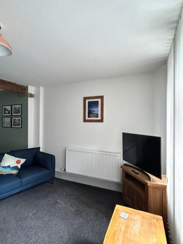 赖厄德Cadwgan House的客厅配有蓝色的沙发和平面电视。
