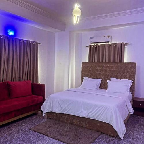 哈科特港Dew Shortlet Apartment的一间卧室配有一张床和一张红色的沙发