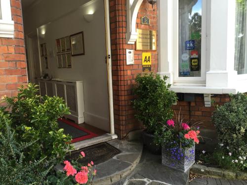 克罗伊登Croham Park B&B - Free Parking & Wi-Fi的门廊上鲜花盛开的房子的前门