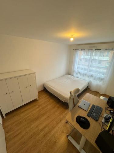 基扬古尔Appartement JO, proche Paris的小房间设有一张床和一张带电脑的书桌