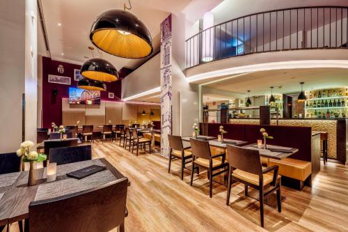 科隆CityClass Hotel Alter Markt的一间带桌椅的餐厅和一间酒吧