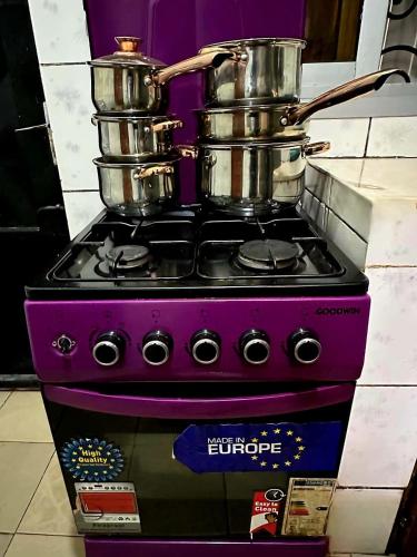 雅温得GOLF HILLS BASTOS的紫色的炉子,上面有锅和平底锅