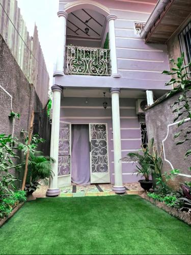 雅温得GOLF HILLS BASTOS的一座带紫色门和绿色草坪的房子