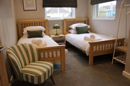 新米尔顿4 Bedroom Getaway New Forest的一间卧室设有两张床、一把椅子和一个窗户。