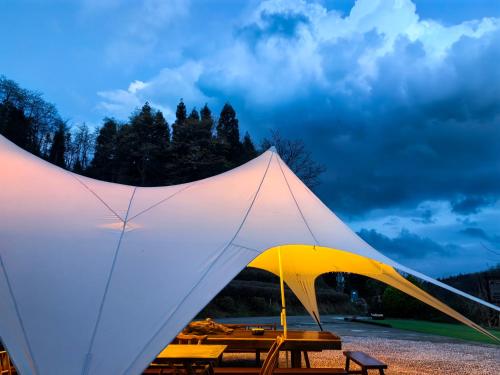 张家界Zhangjiajie National Forest Park Camping的一个带野餐桌的大型白色帐篷
