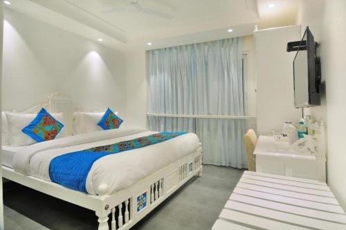新德里Jupiter Plaza Delhi Airport的白色卧室设有一张大床和电视。