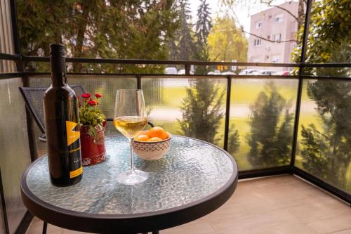 KriževciApartment City Cat的阳台上的桌子上放着一瓶葡萄酒和一杯