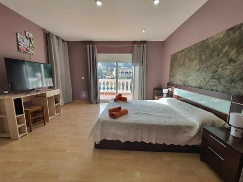 卡隆赫Costa Brava Suites Villa Cèsar的一间卧室配有一张大床和电视