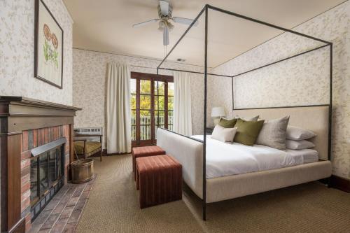 圣巴巴拉De La Vina Inn的一间卧室设有一张天蓬床和一个壁炉