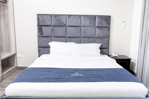 利隆圭The Forty Four Hotel的一间卧室配有一张大床和灰色床头板