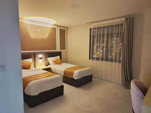 瓦迪穆萨Rakan ApartHotel and Luxury Rooms的酒店客房设有两张床和窗户。