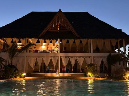 瓦塔穆Nadia&Ale House - Maisha Resort的一座带游泳池的度假村,位于一座建筑前