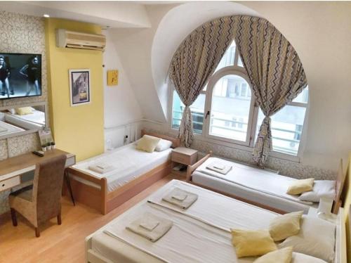 尼什Yellow Diamond的客房设有三张床、一张书桌和一个窗户。