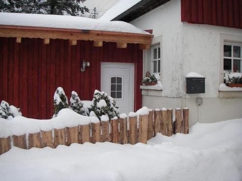 PresseckFerienhaus "Lena"的雪覆盖着栅栏的红色房子