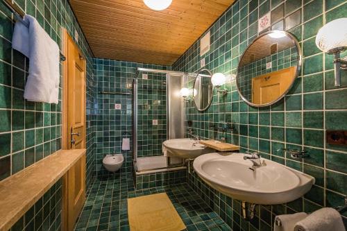 巴特莱辛哈尔Landhotel Sonnleiten的绿色瓷砖浴室设有两个水槽和镜子