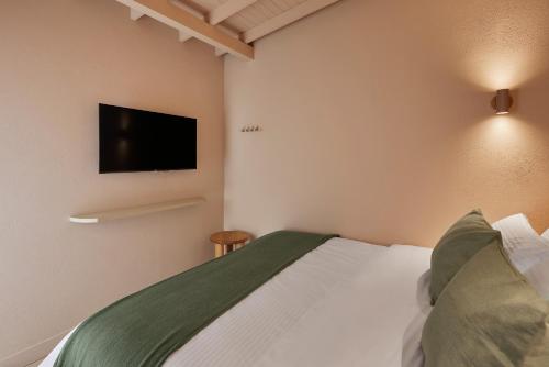 麦德林ANTIPODA HOTEL Boutique的卧室配有一张床铺,墙上配有电视