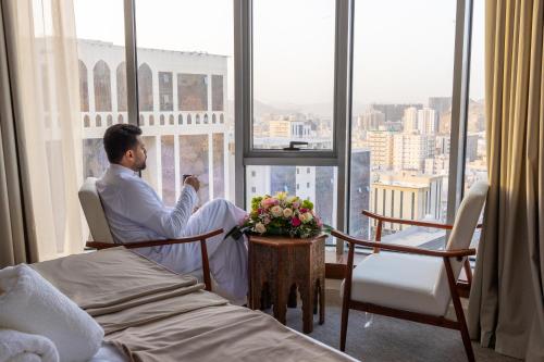 麦加Wassad Hotel Makkah فندق وسد مكة的坐在窗户房间里椅子上的男人