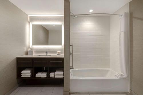 安纳海姆Home2 Suites By Hilton Anaheim Resort的带浴缸、水槽和镜子的浴室