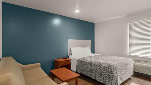 埃文斯维尔埃文斯维尔伍德斯普林套房汽车旅馆的一间卧室设有一张床和蓝色的墙壁