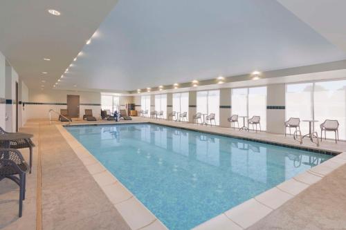 克洛维斯Home2 Suites By Hilton Clovis的酒店客房的大型游泳池配有椅子
