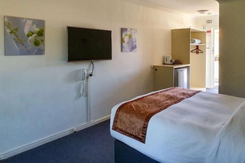 珀斯Econo Lodge Rivervale的一间卧室配有一张床和一台平面电视