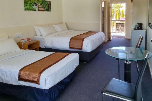 珀斯Econo Lodge Rivervale的酒店客房,设有两张床和一张玻璃桌