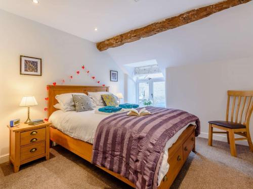 泰德斯韦尔2 Bed in Tideswell 81534的一间卧室配有一张带木制床头板和椅子的床。