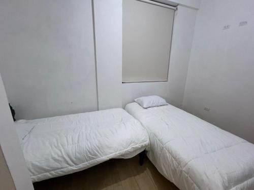 阿亚库乔Mini apartamento en Ayacucho的配有白色墙壁的小客房内的两张床