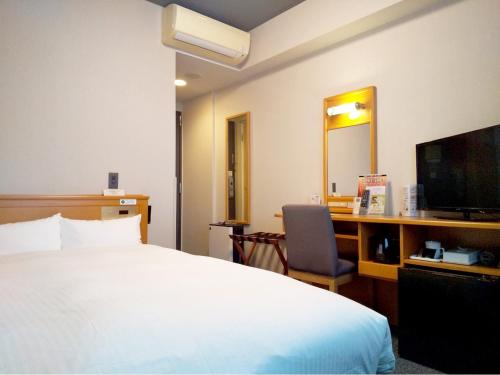 白山市三河国际路线大酒店的酒店客房配有一张床、一张书桌和一台电视。