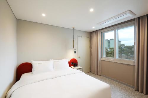 江陵市Hotel The One的卧室设有一张白色大床和一扇窗户。