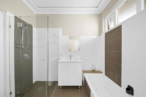 悉尼River View Oasis: Spacious 3-Bed House with Pool的白色的浴室设有水槽和淋浴。