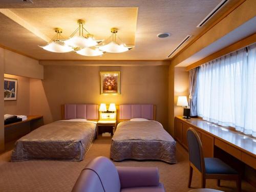 SagaeHotel Symphony Sagae Onsen的酒店客房配有两张床和一张书桌