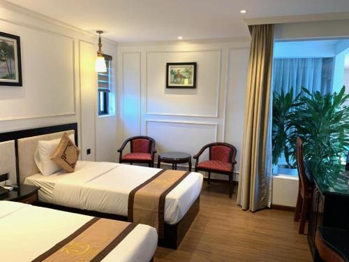 Quang BinhPhong Nha Jasmine Hostel & Roof Top Bar的酒店客房带两张床和一张桌子以及椅子。