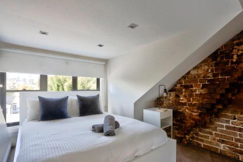 悉尼Spacious 3 Bedroom House Glebe with 2 E-Bikes Included的卧室配有白色的砖墙床