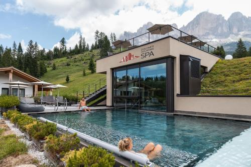 新黎凡特Moseralm Dolomiti Spa Resort的躺在度假村游泳池中的女人