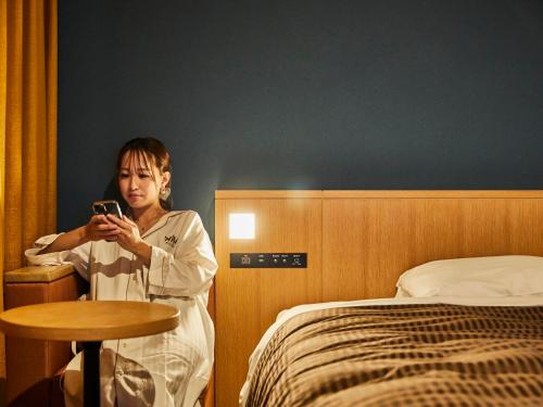 泉佐野关西机场华盛顿酒店的坐在床边看手机的女人