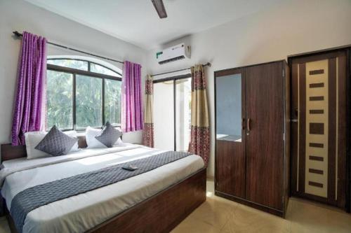 GoaBaga Treasures的一间卧室配有一张大床和紫色窗帘