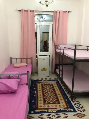 马斯喀特Room center的一间设有三张双层床、粉红色窗帘和地毯的房间