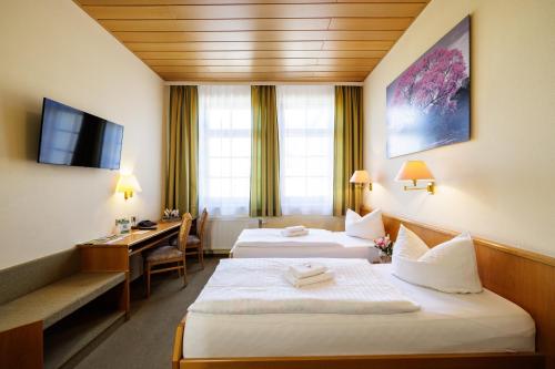 卡门茨Flair Hotel Kamenz的酒店客房配有两张床和一张书桌