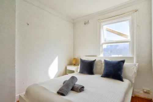 悉尼Delightful 2 Bedroom House Pyrmont 2 E-Bikes Included的一间卧室配有一张带蓝色枕头的床和一扇窗户。