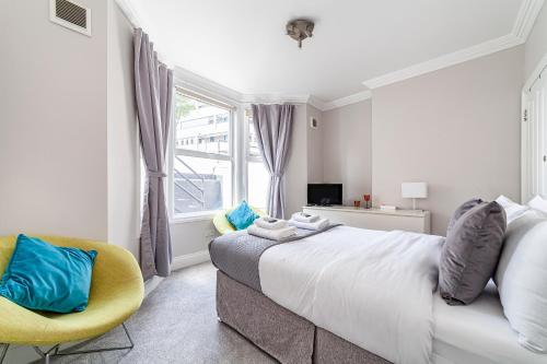 伦敦Amazing 2BR flat wprivate garden, Maida Vale的一间卧室配有一张大床和一张黄色椅子