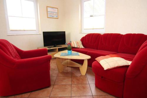 奥斯赛拜-屈隆斯博恩Semi detached house Kuehlungsborn的客厅配有2张红色沙发和电视