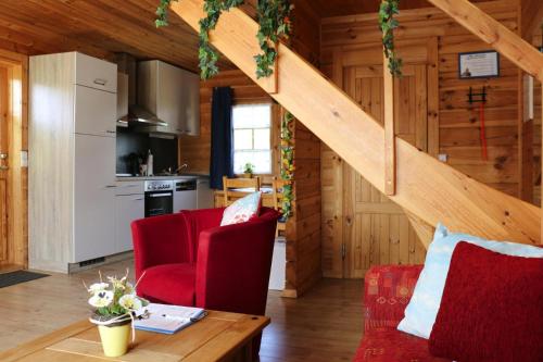 巴特萨克萨Blockhouse in the Fuchsbau Bad Sachsa的一间厨房和一间带红色椅子及楼梯的客厅