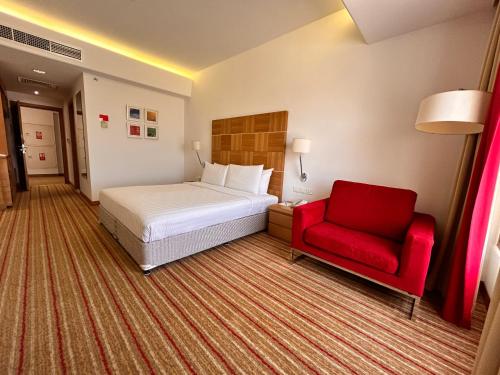 马斯喀特Golden Tulip Muscat的酒店客房,配有一张床和一张红色椅子