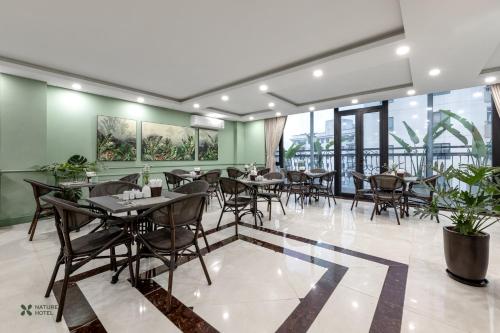 河内Nature Hanoi Hotel的餐厅设有桌椅和窗户。
