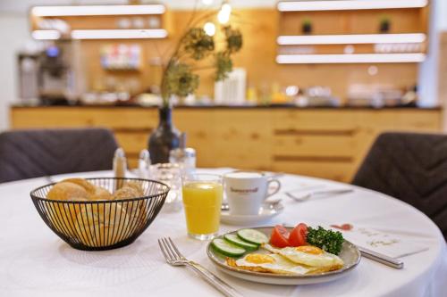 SitzenbergLandgasthof Schmid - Unterkunft & Restaurant的餐桌,上面放着一盘食物和一杯橙汁
