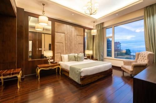 西姆拉The Orchid Hotel Shimla的卧室配有床、椅子和窗户。