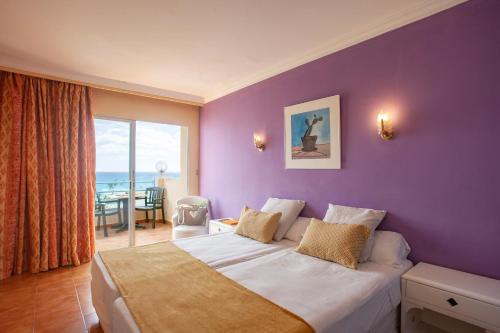 萨科马BJ Playa Blanca的一间卧室设有紫色墙壁、一张床和一张桌子