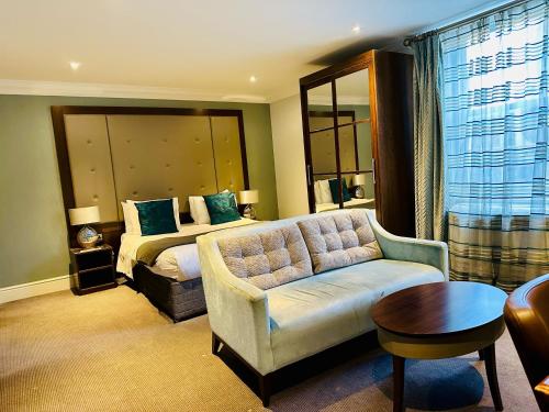 剑桥Lensfield Hotel的一间卧室配有一张床、一张沙发和一张桌子