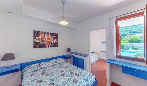 尼斯波特Elba Island Resort Pool & Tennis的一间卧室设有蓝色的床和窗户。